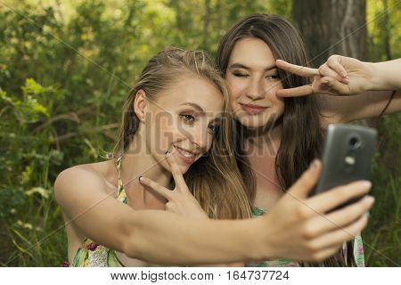 Happy Teenage Girls Taking Selfshot Or Selfy Picture Of Themselves With Mobile Phone Outdoors Over G