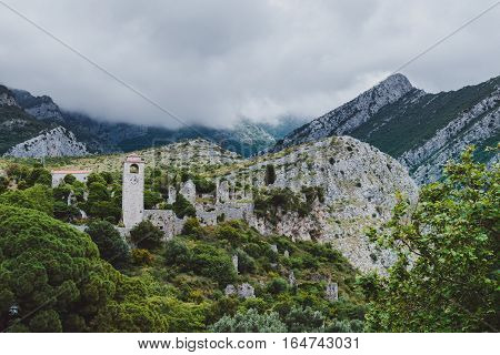 Ancient stone ruins and clock tower at Old Bar town on the cloudy mountains landsape, Montenegro. Stari Bar - ruined medieval city on Adriatic coast, Unesco World Heritage Site.