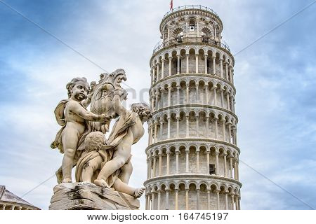 Leaning Tower of Pisa and the Fountain with Angels. Piazza dei Miracoli. Blue cloudy sky. Tuscany Italy.