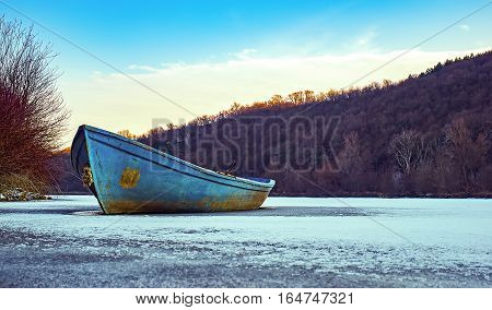 Blue fishing boat on a frozen lake.