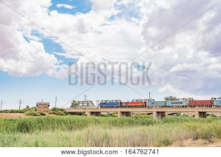 MODDERRIVIER SOUTH AFRICA - DECEMBER 25 2016: A train crossing the Riet River at Modderrivier. The Blockhouse used by British soldiers to defend the bridge during the second Boer War is visible