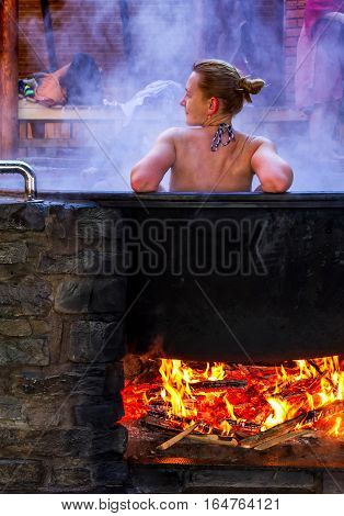 Lumshory Ukraine - January 10 2017: A woman bathes in a the cast iron vat with mineral water containing hydrogen sulphide. Water in cast iron vats heated to 40-45 degrees Celsius.