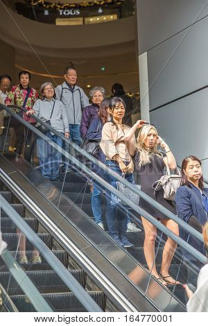 Hong Kong, China - December 6, 2016: asian people with shopping bag down the escalator out of the mall in Causaway Bay Jardine's Crescent market, a popular roadside bazaar to shop.