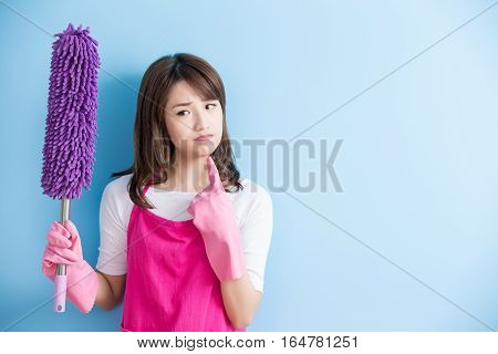 beauty housewife take feather duster and unhappy isolated on blue background asian