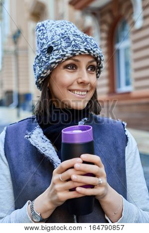 The girl with thermo cup, is walking through the old town