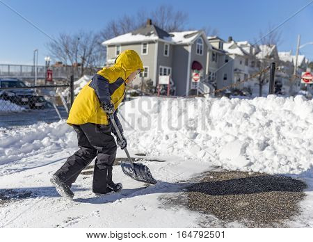child cleans snow in the yard. boy shoveling snow. the concept of selfless assistance, citizen responsibility