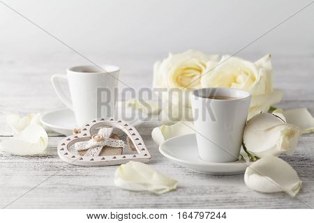 White roses and two white cups on rable