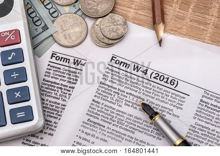 tax form w4 with pen and us dollar calculator and pen.