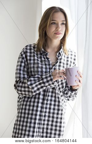 Melancholy girl having coffee looking out the window