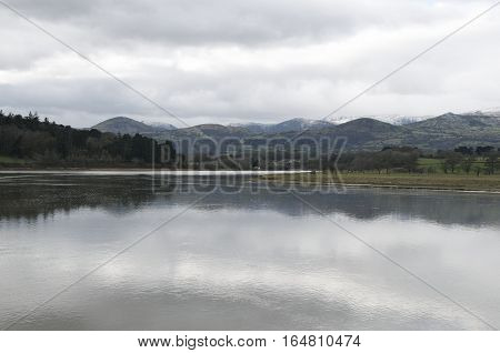 Snow capped mountains behind a tranquil river with beautiful reflection of the mountain range in the water