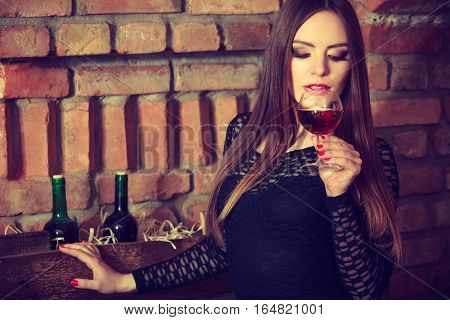 Woman Tasting Wine In Rural Cottage Interior