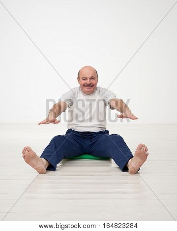 Elderly man practicing yoga or fitness. Positive mood on sports activities