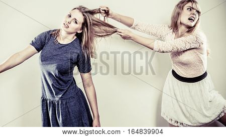 Aggressive mad women fighting each other pulling hair. Two young girls struggling win catfight. Violence.