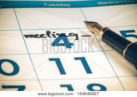 calendar with black pen focus on text meeting