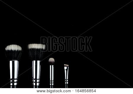 Makeup brushes lying on a black background