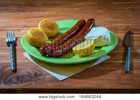 Grilled sausages with corn bread and white cheese served in a plate on a wooden table