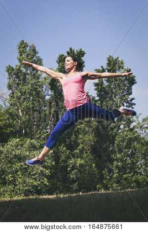 Beautiful woman doing jumping exercises in nature