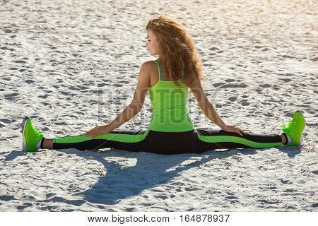 Young Athletes - Gymnast With Curly Hair, Light Green Suit And Sneakers Doing The Splits On The Beac