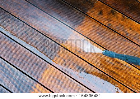 cleaning terrace with a power washer - high water pressure cleaner on wooden terrace surface