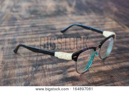 The old glasses legs are wrapped with masking tape is placed on the table.