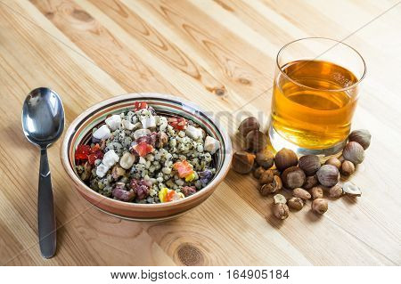 Christmas kutia and uzvar. Traditional ukrainian cereal wheat porridge with raisins nuts poppy seeds honey and candied fruit in earthenware bowl with dried fruit drink on natural wood table