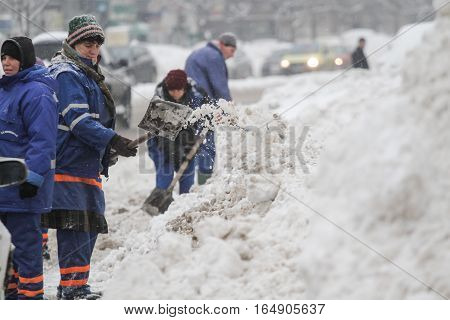 Bucharest Romania January 27 2014: City workers shovel snow to clean the road after a snowfall in Bucharest.