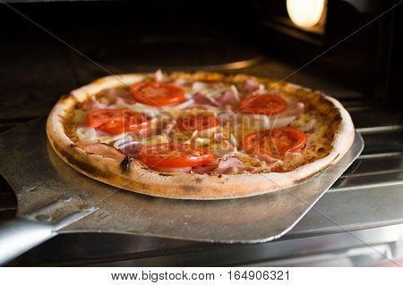 Ready-made pizza is removed from the furnace. Delicious hot crispy pizza. Food delivery