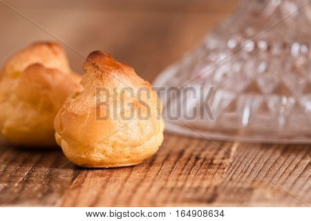 Detail of sweet cream puffs on wooden table.