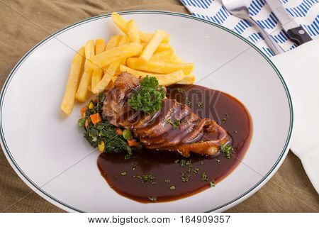A nice dish of roasted duck breast confit in orange sauce served with fries on the table