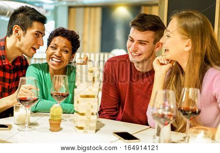 Happy friends playing board game in pub winery restaurant - Young cheerful people having fun toasting red wine together - Leisure and friendship concept - Focus on black afro woman - Warm filter