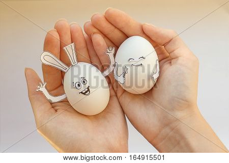 Two Easter smiling eggs in his hands. Egg-rabbit
