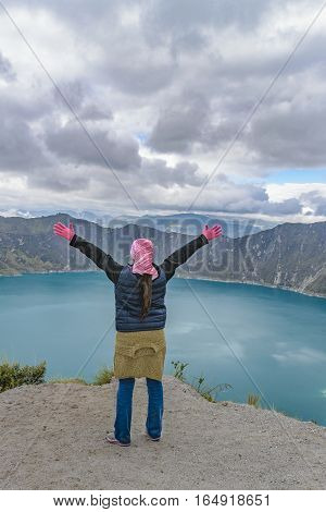 Young woman with hands up at watching the view at Quilotoa lake Latacunga Ecuador