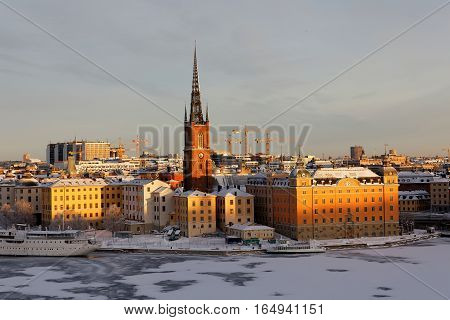 STOCKHOLM - JAN 08 2017: Old beautiful buildings at Riddarholmen lit with warm light a cold winter morning ice on the sea. January 08 2017 in Stockholm Sweden