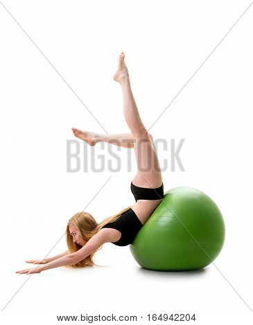 Long haired blonde in black shorts and briefs lying on her stomack on green big fitball posing in studio with her legs streching up