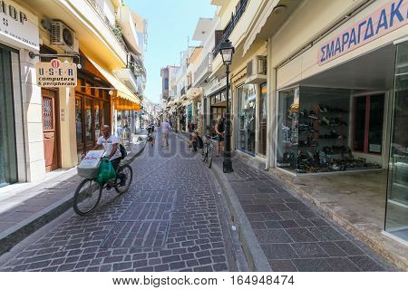 Rethymnon, Island Crete, Greece - June 23, 2016: A deliveryman of pizza on the bicycle is on the narrow street of Rethymnon (part of Old Town)