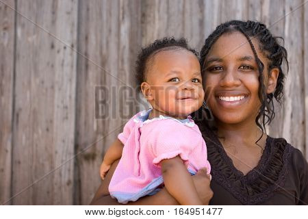 Teenage African American mother holding her daughter.