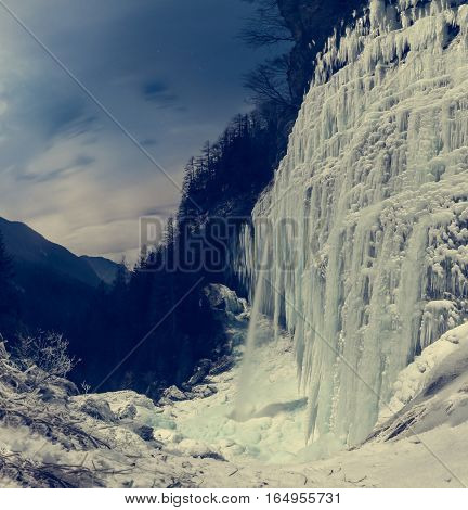 Frozen waterfall at night. Icicles hanging from sheer wall of Pericnik Slap, Vrata in Slovenia.