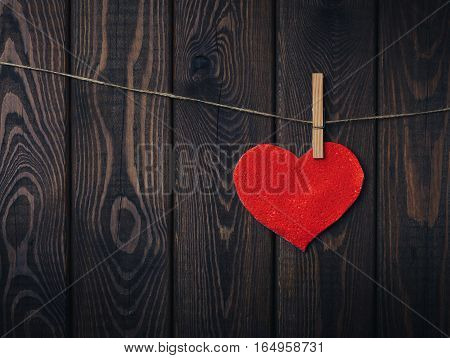 Red heart on a rope with clothespin on a wooden background. Valentines Day concept. Copy space.