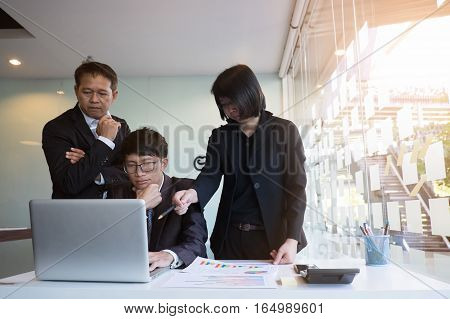 business Teamwork looking at report in laptop computer and discussion in office. Film effected photo.