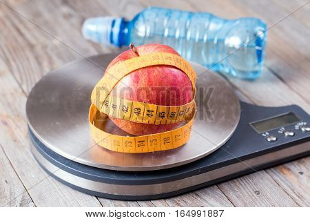 Measuring tape wrapped around a apples on wooden background