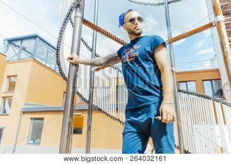 Portrait Of Young Vaping Man With Dreadlocks At Art Object Background. Vapor Concept. Vaping E-cigar