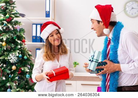 Colleagues exchaing christmas presents in office