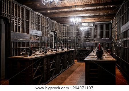 The Wine Room With A Lot Of Buttles, Wooden Shelves And Red Candles