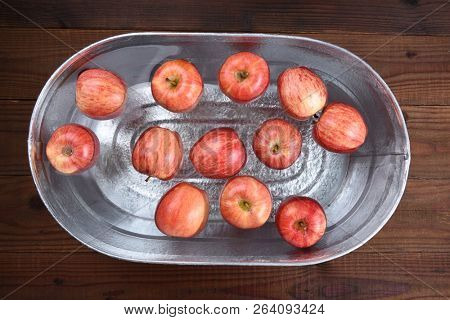 High angle horizontal shot of a metal tub filled with water and apples for the Halloween custom of Apple Bobbing.