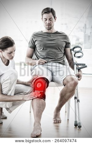 Physiotherapist examining man with crutches against highlighted pain