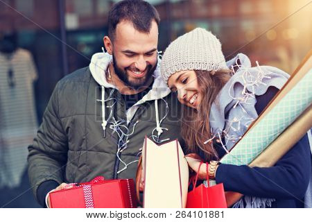 Portrait of happy couple with shopping bags after shopping in city