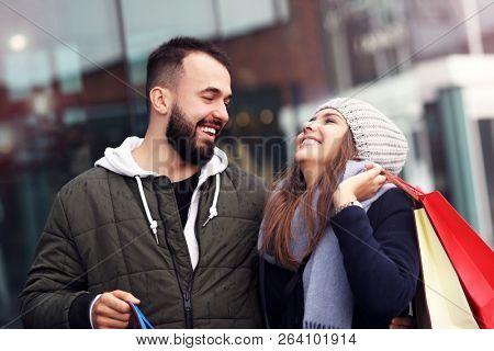 Portrait of happy couple with shopping bags after shopping in city