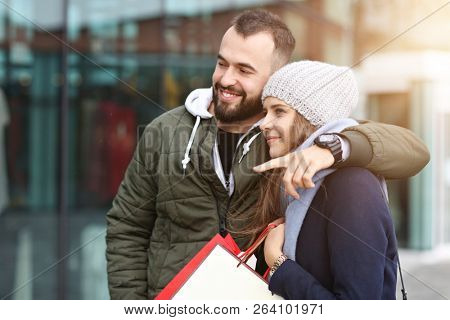 Portrait of happy couple with shopping bags after shopping in city
