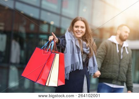 Portrait of happy couple with shopping bags after shopping in city