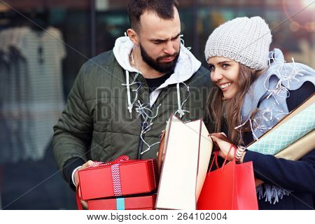Portrait of happy couple with shopping bags after shopping in city